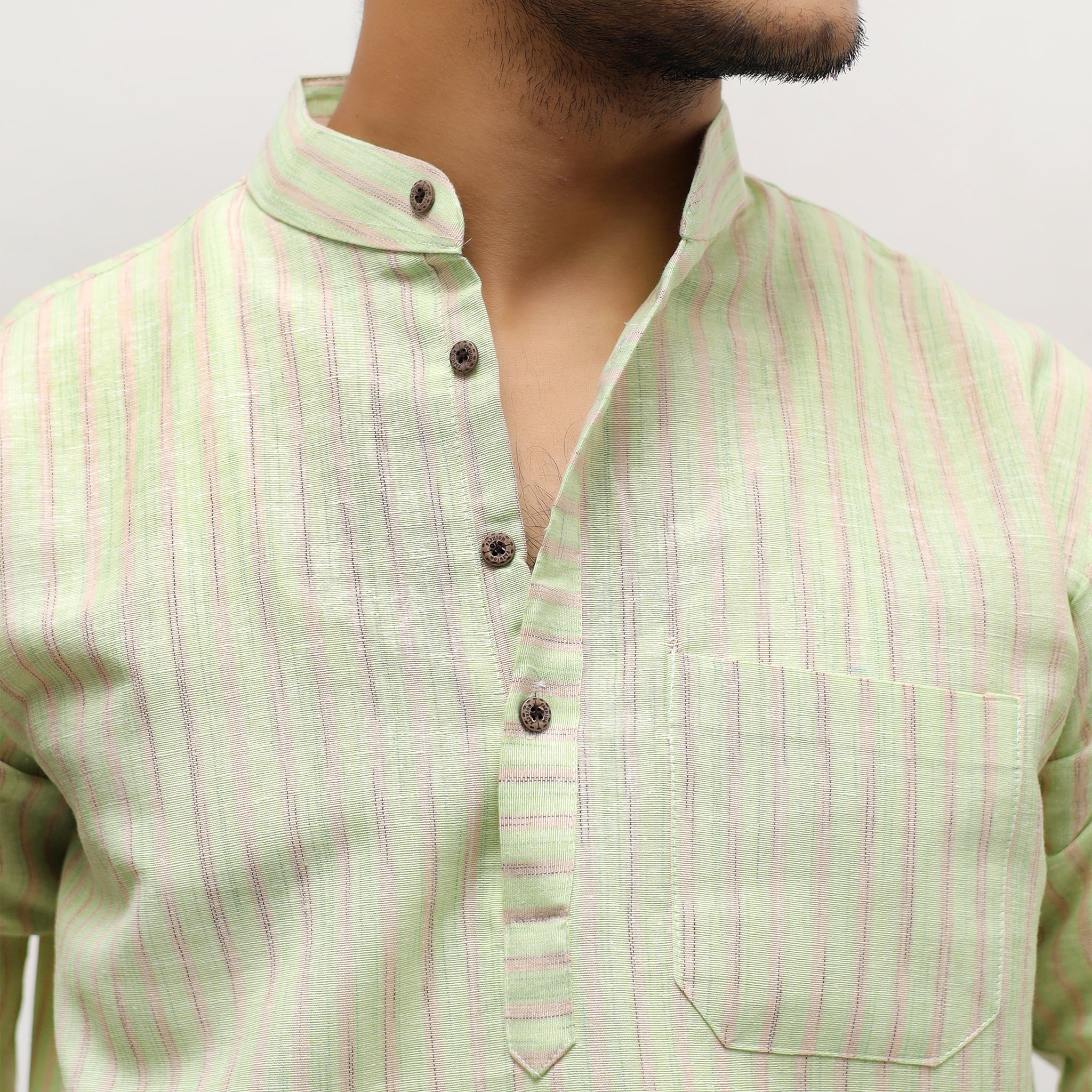 Light green shirt with pink stripes worn by a person on a plain background