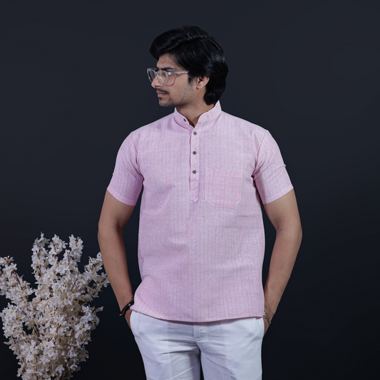 Man wearing a pink shirt and white pants against a dark background